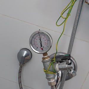 מד לחץ מים מחובר לצינור עם חוטים ירוקים