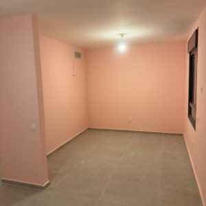 חדר ריק עם קירות ורודים ורצפת אריחים אפורה