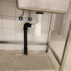 כיור נירוסטה עם צנרת פלסטיק מתחתיו