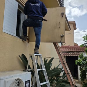 אדם על סולם מתקין תריסים בבית