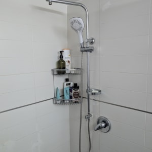 מקלחת עם ראש מקלחת ומדף עם מוצרי טיפוח