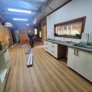 אדם מתקין פרקט עץ בחדר עם קירות עץ