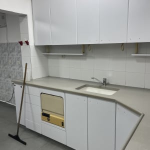 מטבח נקי עם ארונות לבנים ומגב על הרצפה