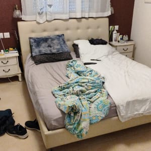 מיטה עם מצעים צבעוניים ושלטים על השידה