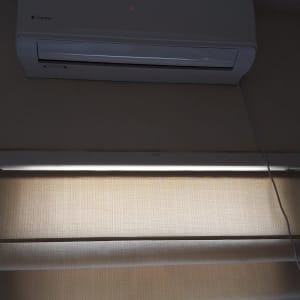 מזגן קיר לבן מותקן מעל חלון עם וילון