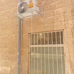 יחידת מיזוג אוויר מותקנת על קיר אבן חיצוני