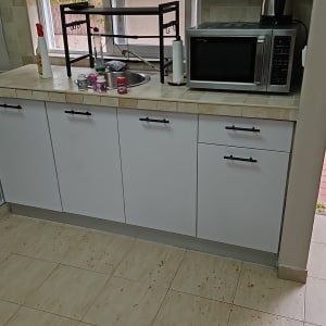 מטבח עם ארונות לבנים ומשטח עבודה