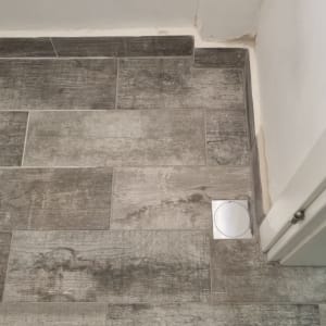 רצפת אריחים עם פתח ניקוז עגול בפינה