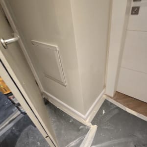 קיר צבוע עם דלת פתוחה ורצפה מכוסה בניילון להגנה