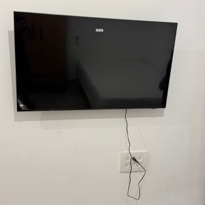 טלוויזיה תלויה על הקיר עם כבל חשמל מחובר