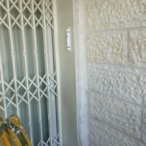 סולם ליד דלת עם תריס מתכת על קיר אבן