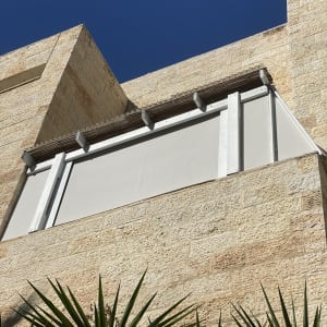 סוכך לבן מותקן על קיר אבן חיצוני