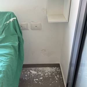 קיר עם תיקוני טיח ופסולת על הרצפה