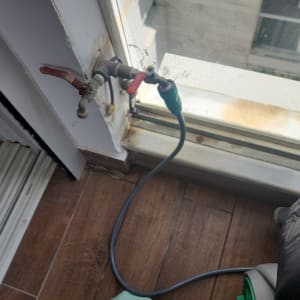 ברז מים עם צינור מחובר ליד חלון