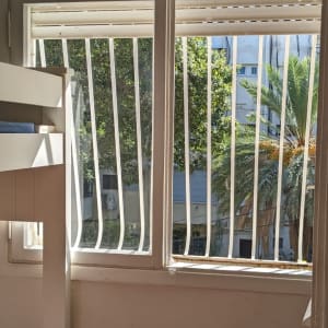 חלון עם סורגים לבנים ותריסים פתוחים