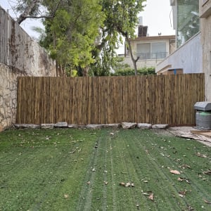 גדר עץ במרפסת עם דשא ועצים ברקע