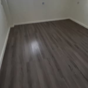 חדר ריק עם רצפת פרקט כהה וחלון