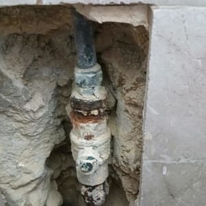 צינור מים עם חלודה בקיר פתוח