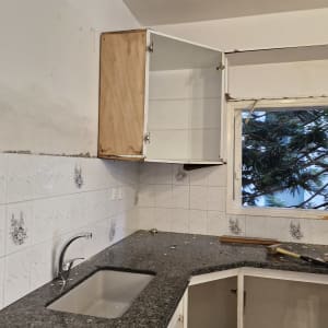 מטבח בשיפוץ עם ארונות פתוחים וכלים על השיש