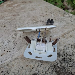 שקע חשמלי מפורק עם חוטים חשופים וחלודים