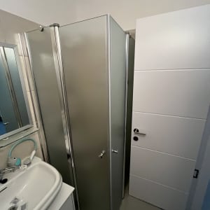 מקלחון עם דלתות זכוכית ליד כיור בחדר אמבטיה