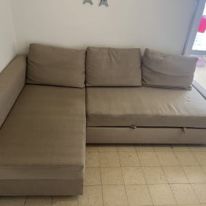 ספה חומה בפינת חדר עם כריות על רצפת אריחים