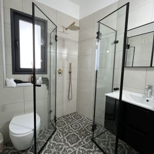 מקלחון זכוכית עם ראש מקלחת מוזהב ורצפת אריחים מעוצבת