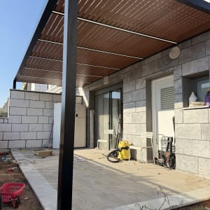 פרגולת אלומיניום שחורה עם שלבי דמוי עץ ותאורת לדים מובנית במרפסת