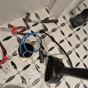 כלים לתיקון נזילות על רצפה, כולל פטיש וצינור