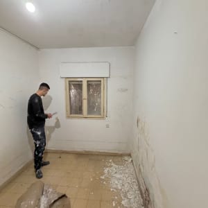 אדם בחדר עם קירות מתקלפים ועבודות צבע