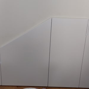 ארון לבן עם דלתות משופעות מתחת למדרגות