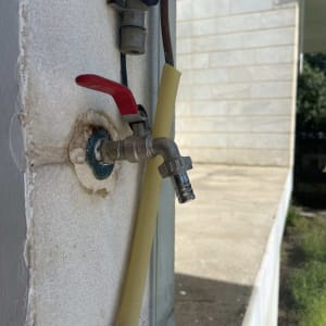 ברז מים עם ידית אדומה על קיר חיצוני