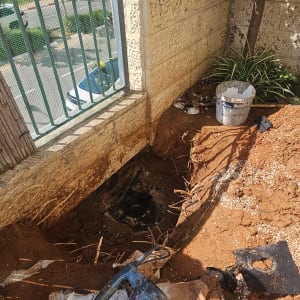 חפירה וכלי עבודה ליד קיר אבן ועץ