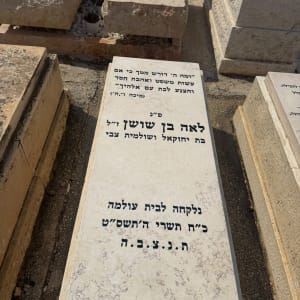 מצבת שיש בהירה עם כיתוב מושחר וחריטה בבית עלמין