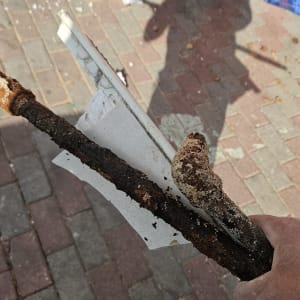 צינור חלוד על רקע מדרכה