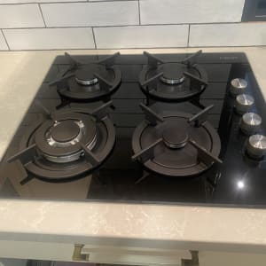 כיריים גז שחורות עם ארבעה מבערים וכפתורי שליטה כסופים