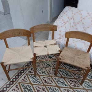 שלושה כיסאות עץ עם מושבים קלועים על רצפה מעוטרת