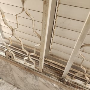 סורג חלון מתכת עם חלודה על רקע שיש