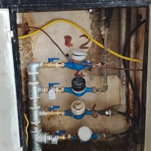 מד מים עם צינורות וחיבורים בקיר
