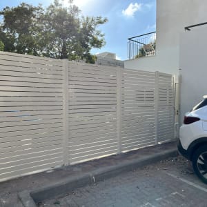 גדר אלומיניום לבנה ליד רכב חונה