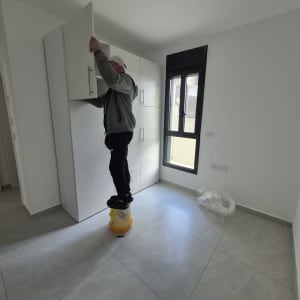 אדם מתקין ארון בחדר ריק עם חלון