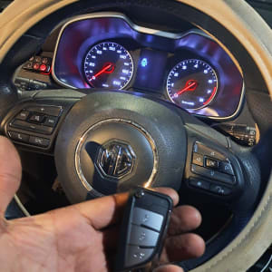 מפתח רכב חכם ביד מול הגה ומד מהירות