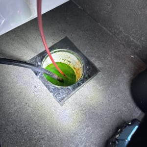 צינור אדום בתוך פתח ניקוז עם נוזל ירוק