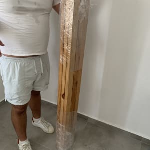 אדם מחזיק עמוד עץ עטוף בניילון