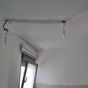 שני נורות תלויות מהתקרה בחדר עם חלון פתוח