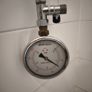 מד לחץ מים מותקן על קיר לבן