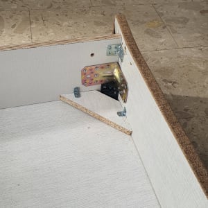 חיבורי מתכת בפינת רהיט מעץ על רצפה