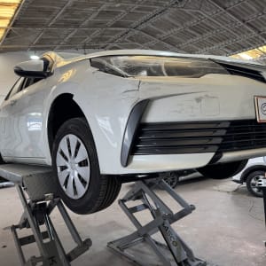 רכב לבן על מעלית במוסך עם שלט מוקד הרכב חיפה