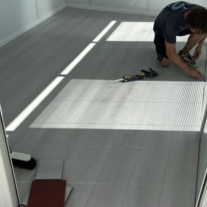 אדם מתקין פרקט בחדר עם רצפת עץ בהירה