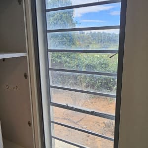 חלון אלומיניום עם נוף חיצוני ועץ ירוק